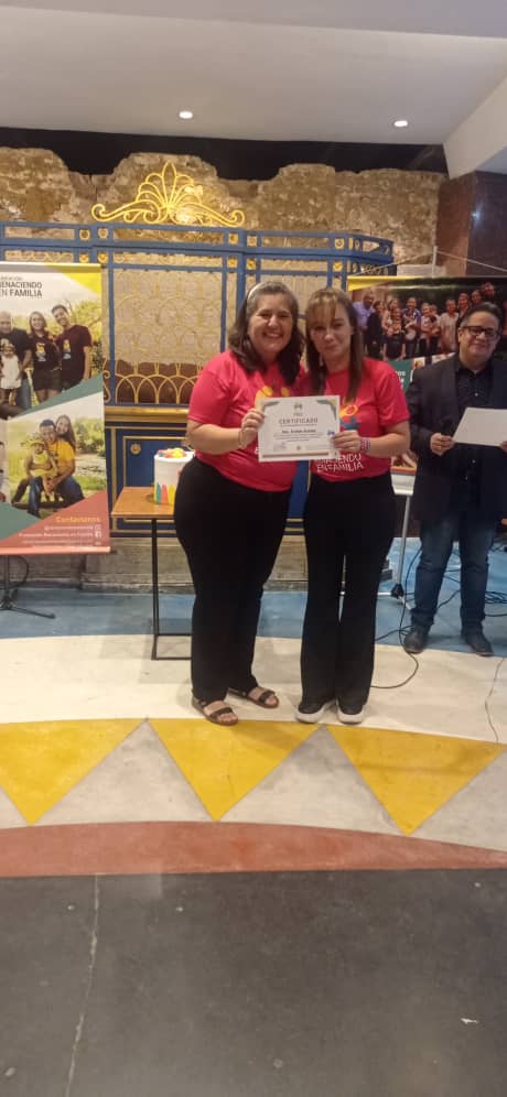 man wearing a black jacket, white shirt, blue jeans, and brown boots, playing a white electric guitar while sitting on an amp